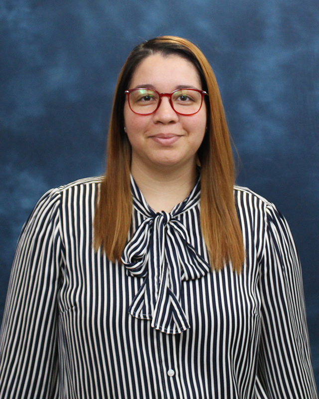 Program Assistant Kylie Alvarez smiling with a blue background behind her.