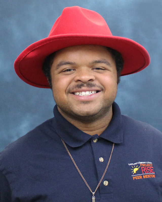 Peer mentor Tyler smiling in front of a blue background